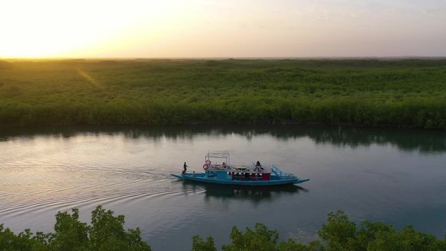 2020 - beautiful aerial over small boat moving along the Gambia river in West Africa through mangrove forests and winding bends.