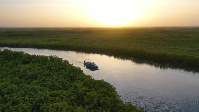 2020 - beautiful aerial over small boat moving along the Gambia river in West Africa through mangrove forests and winding bends.