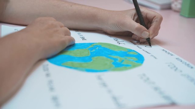 Close up on hands writing all will be ok in many languages around colorful world