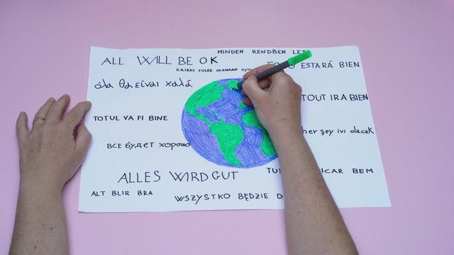 Hand of woman color world drawn on paper with all will be ok motto in all idioms