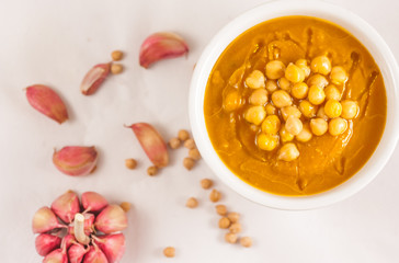 Chickpeas soup in a bowl with olive oil and purpple garlic. Soup bowl. Top view