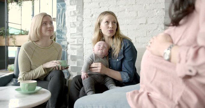 Pregnant woman relaxing with friends and baby at cafe restaurant