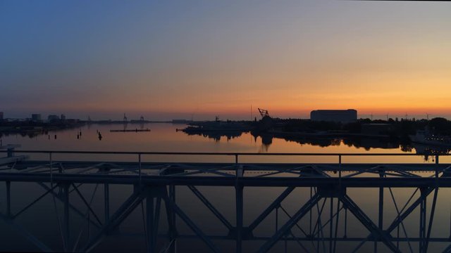 Slow rising drone video in the golden hour with an old structure in front of a beautiful sunrise and calm harbour water in Copenhagen.