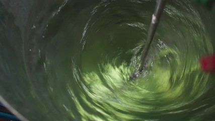 Top view of professional motorized chemical liquid mixer tank powered on, creating a beautiful circular water whirl.