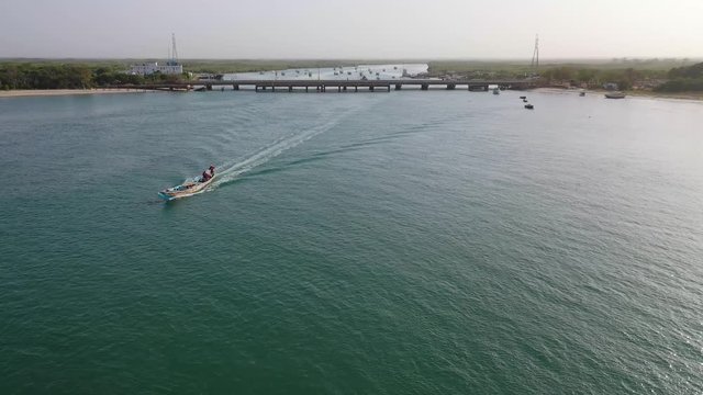 2020 - beautiful aerial over long boat moving along the Gambia river in West Africa through mangrove forests and winding bends.