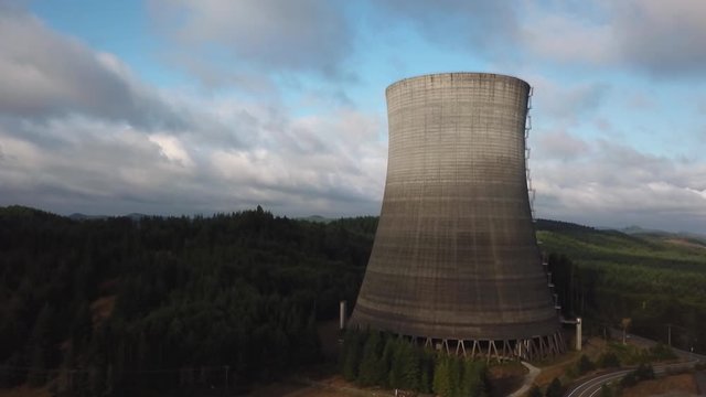 The Satsop Nuclear Power Plant In Elma, Washington Surrounded By Lush Pine Trees Under The Bright Cloudy Sky - Aerial Drone Shot