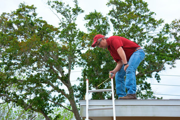 Wind mitigation inspector wearing safety goggles doing inspection on new roof to create a report and risk rating for homeowner to send to their insurance company to receive deductions in policy costs. - 342214251