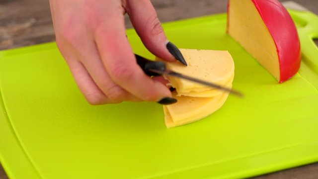 Stacking Thin Quarter Slices Of Dutch Edam Cheese On A Chopping Board  - Closeup Shot