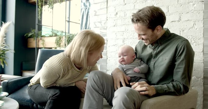 Couple with baby relaxing in trendy cafe restaurant together, family weekend activities