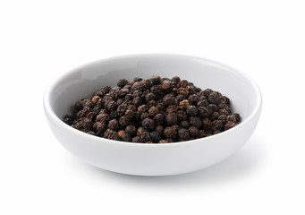 Black pepper in a plate placed on a white background