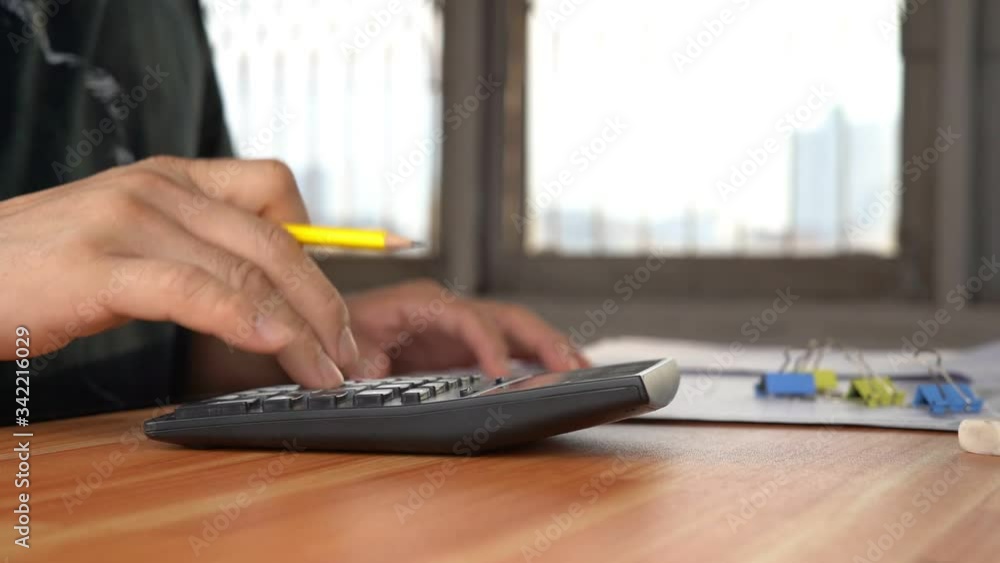 Poster a man using a calculator press numbers to calculate monthly expenses.