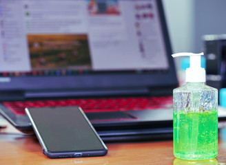 Green gel alcohol With a mixture of aloe vera in a pump-like bottle placed on the work desk, Together with the background of the smart phone and laptop.