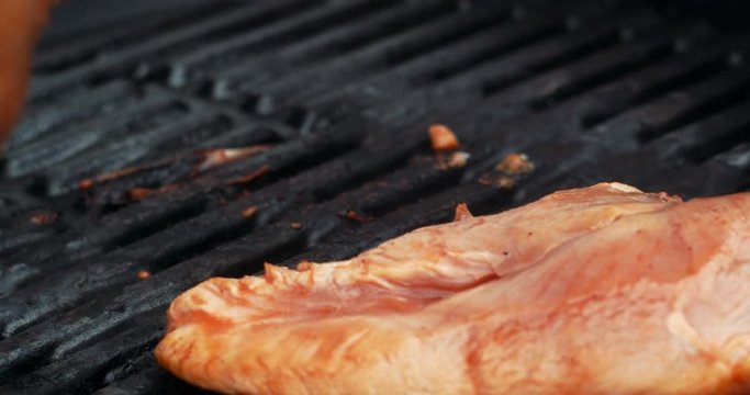 Turning arround a marinated Chicken breast on a gas grill.