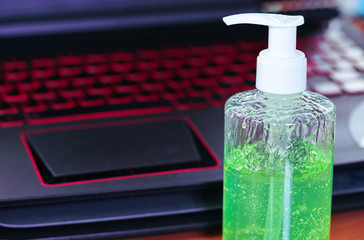 Green gel alcohol With a mixture of aloe vera in a pump-like bottle placed on the desk Together with the background of the laptop.