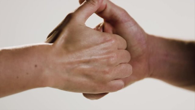 A male and female hand combat in a friendly game of thumb wars with the female winning in the end.
