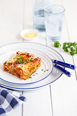 A plate of lasagna with eggplant and zucchini served with  grated cheese
