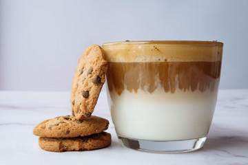 Glass of dalgona coffee and cookies, on a marble background. Korean drink.