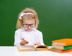 pretty attractive little girl children using book studying having problem in chalkboard background