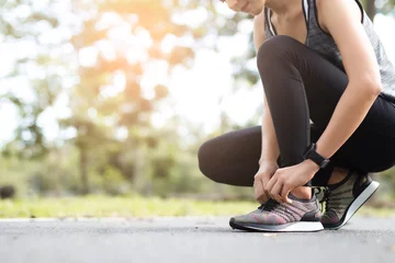 Foto op Plexiglas Young woman tying jogging shoes. © ibravery