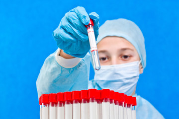 Female medical worker holding test tube on a blue background. Coronavirus test.