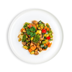 Plate of Vegan vegetable and mushroom stir-fry with carrots, broccoli, zucchini and capsicum isolated on white 