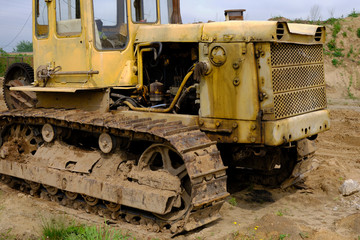 Fototapeta na wymiar An old rusty, abandoned yellow bulldozer in a field.