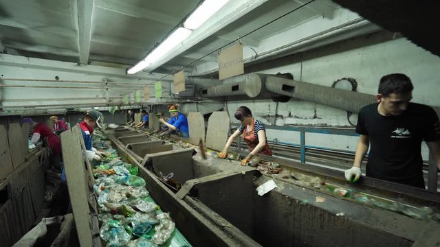 RUSSIA, TVER - JUNE 20, 2019: Workers manually sort plastic and other waste on a recycling conveyor inside a factory.  