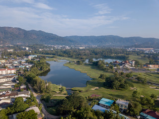 Beautiful lake located on a golf course surrounded by houses and mountains at dawn, photo from a drone. In the lake the reflection of the sky. Great background for travel and golf advertising.