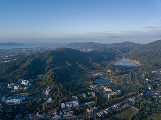 Naklejka premium Beautiful lake located on a golf course surrounded by houses and mountains at dawn, photo from a drone. In the lake the reflection of the sky. Great background for travel and golf advertising.