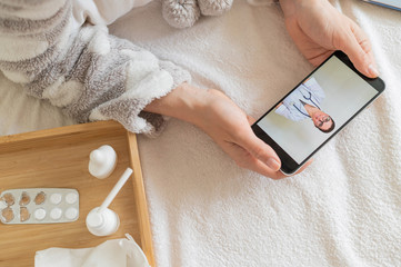Unrecognizable woman with a cold talking to a doctor through video chat on a smartphone. friendly...