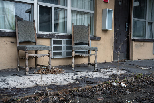 Old cloth chairs in the front of an abandoned and vandalized motel