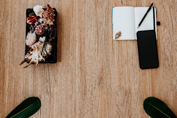 Flat lay, top view of a notepad with white paper and pen for planning an upcoming trip, or freelancer plan. Smartphone to view the route. Seashells