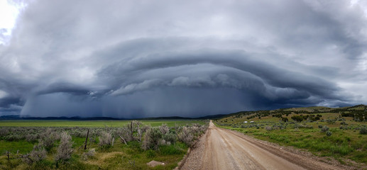 Panoramic of wall cloud with dirt road leading into storm