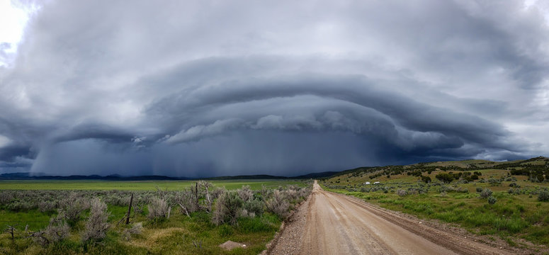 Panoramic of wall cloud with dirt road leading into storm