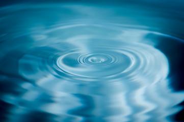 Water drops splash and circle reflextion background.Close up fresh water drops falling into the water and ripples of light blue.