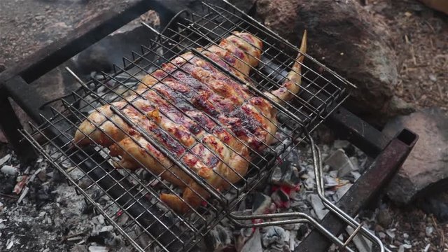 grilling whole chicken on open fire outdoor cooking panning shot