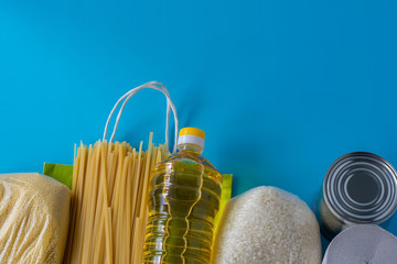 Spaghetti, rice, couscous, olive oil, canned food, toilet paper on a blue background. A paper bag with food isolates the food crisis from isolation. The concept of food delivery, donation, coronavirus