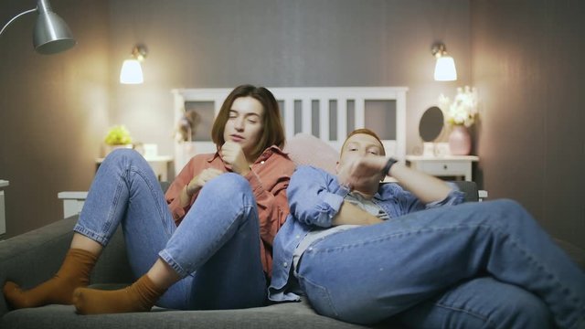 Couple watching attentively football match on tv. feeling anxious supporting their team and beeing disappointed because of loss. Sports fans sad of team losing game.