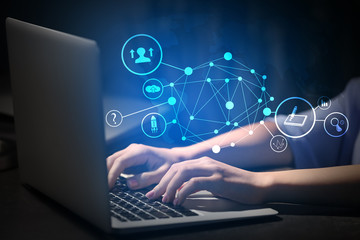 Woman working on laptop at table in evening, closeup