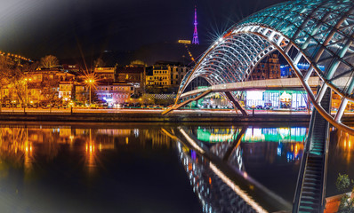 Side night view of  illiuminated the bridge of peace and old town in the background. Sighseeing objects and architecture in Tbilisi.Georgia.2020