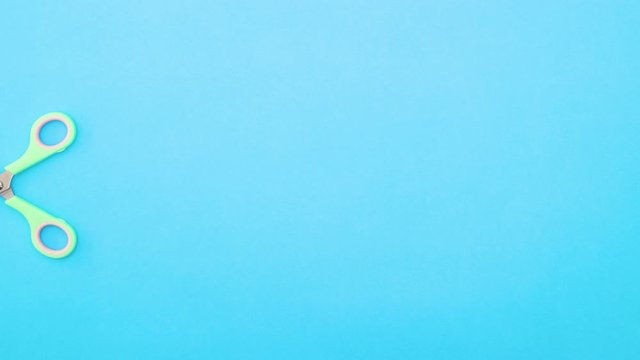 Scissors cutting colored papers that appear on blue background - Stop motion