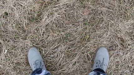 legs in gray boots standing on the field with dry grass
