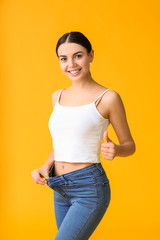 Young woman in loose clothes on color background. Weight loss concept