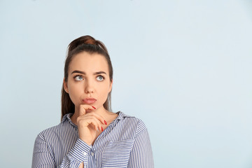 Portrait of thoughtful young businesswoman on color background