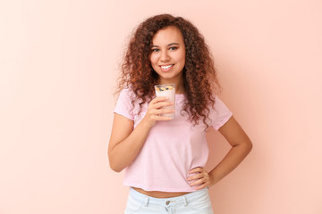 Young woman with tasty yogurt on color background