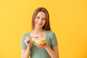 Young woman with tasty yogurt on color background