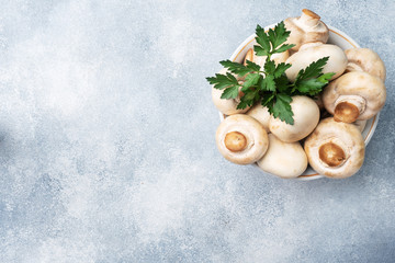 Raw mushrooms champignons in a plate with a sprig of parsley. Copy space.