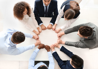 Group of business people putting hands together in office, top view. Unity concept