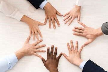 Group of business people putting hands together in office, top view. Unity concept