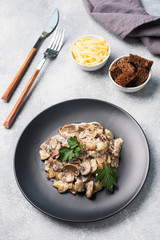 Stewed mushrooms champignons in sauce with sour cream and cheese parsley on a plate.